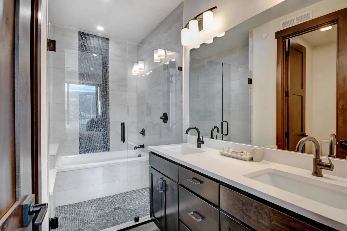 A spa-like bathroom with a double sink vanity, a modern shower area, and ample natural light. The design is elegant and calming, echoing a high-end hotel experience.